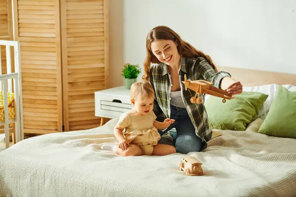 Eine junge Mutter schätzt die Zeit mit ihrer kleinen Tochter, während sie zusammen auf einem Bett spielen. — Stockfoto