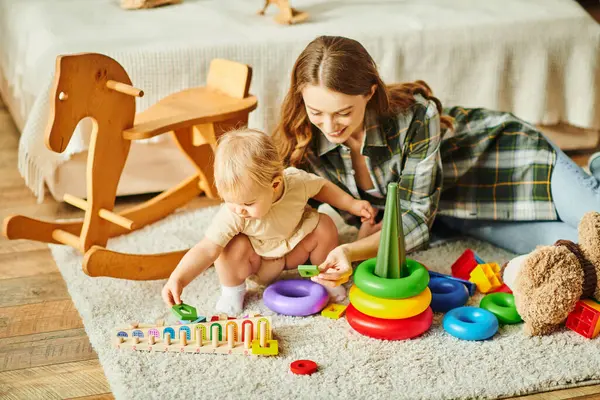 A young mother is playfully interacting with her toddler daughter on the floor, creating a heartwarming and precious moment. — Stock Photo