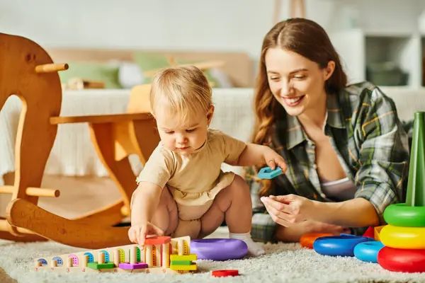 A young mother joyfully playing with her baby daughter on the cozy floor of their home. — Stock Photo