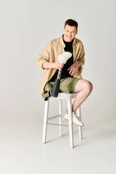 Bello uomo in abbigliamento casual con gamba protesica seduta su sgabello. — Foto stock