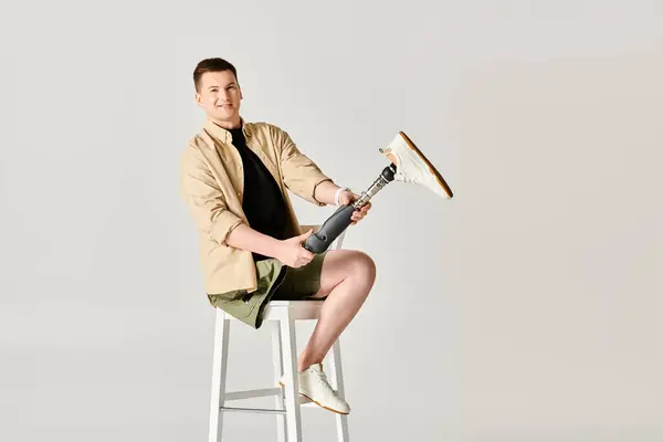 Good looking man with a prosthetic leg confidently sits on top of a stool. — Stock Photo