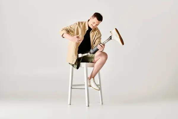 Beau homme avec la jambe prothétique pose activement tout en étant assis sur un tabouret. — Photo de stock