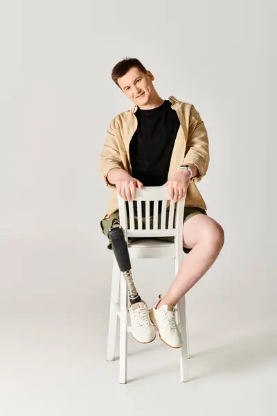 Красивый мужчина с протезной ногой гордо сидит на белом стуле. — стоковое фото