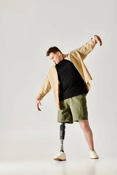 A handsome man with a cast on one leg and a prosthetic on the other, striking a dynamic pose. — Stock Photo
