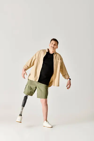 Un bel homme avec une jambe prothétique posant activement dans une chemise noire et un short vert. — Photo de stock