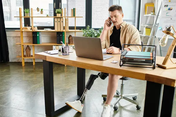 Un bel homme d'affaires avec une jambe prothétique travaillant sur un ordinateur portable à un bureau. — Photo de stock