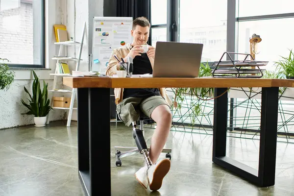 Un bel homme d'affaires avec une jambe prothétique travaille avec diligence sur son ordinateur portable à un bureau élégant. — Photo de stock