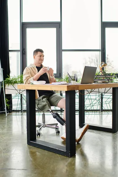 A handsome businessman with a prosthetic leg working diligently on a laptop at a desk. — Stock Photo