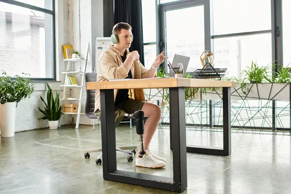 Handsome businessman with prosthetic leg sitting at desk, using laptop. — Stock Photo