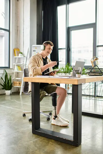 Un bell'uomo d'affari con una gamba protesica che lavora diligentemente sul suo portatile su una scrivania. — Foto stock