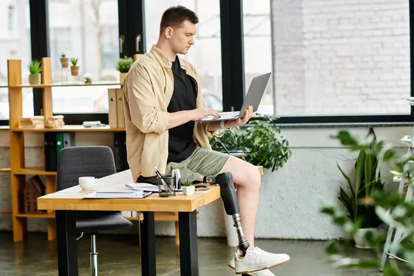 Handsome businessman with a prosthetic leg working at a desk with a laptop computer. — Stock Photo