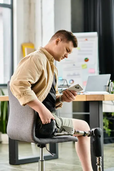 Businessman with prosthetic leg engrossed in phone while sitting on chair. — Stock Photo