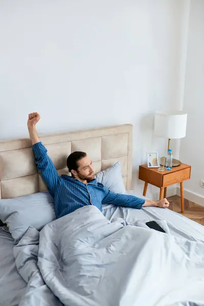 Hombre guapo pacíficamente se acuesta en la cama, saludando a la mañana. - foto de stock