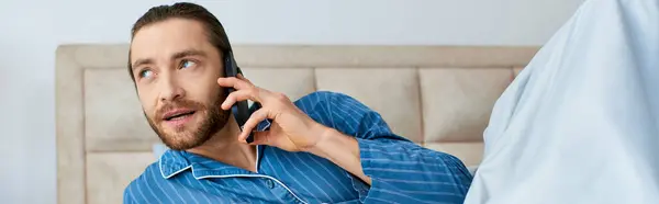 A man in pajamas chatting on a cell phone. — Stock Photo