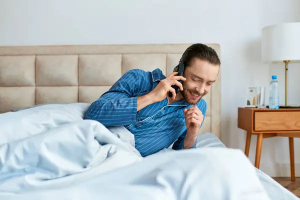 Bonito homem na cama fala no celular. — Fotografia de Stock