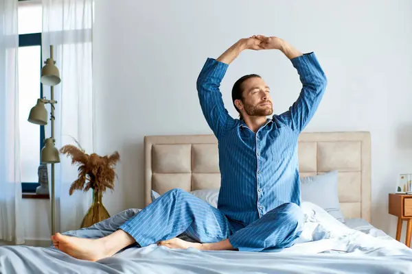 Schöner Mann beim morgendlichen Yoga im Bett, Arme zur Entspannung erhoben. — Stockfoto