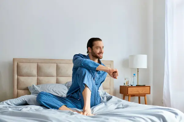 Um homem de pijama senta-se pacificamente em uma cama. — Fotografia de Stock
