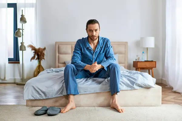 Handsome man in pajamas on top of a bed. — Stock Photo