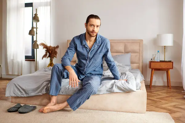 Schöner Mann sitzt auf Bett im gemütlichen Schlafzimmer. — Stockfoto