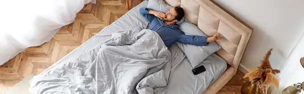 Ein Mann liegt friedlich auf einem Bett mit einer kuscheligen Decke. — Stockfoto