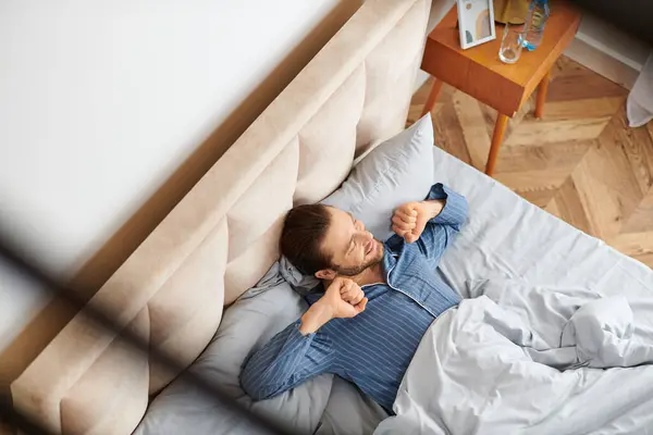 Um homem bonito deitado pacificamente em uma cama em um quarto sereno. — Fotografia de Stock