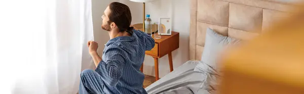 A man sits on a bed, peacefully gazing out the window in the morning. — Stock Photo