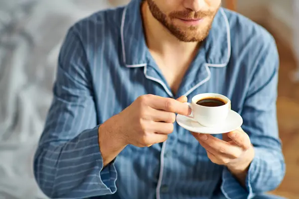Um homem bonito de pijama desfrutando pacificamente de uma xícara de café. — Fotografia de Stock