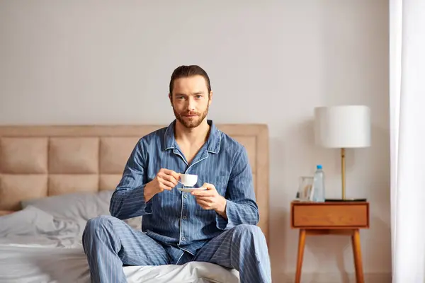 Um homem em ambiente sereno manhã desfrutando de uma xícara de café em uma cama. — Fotografia de Stock