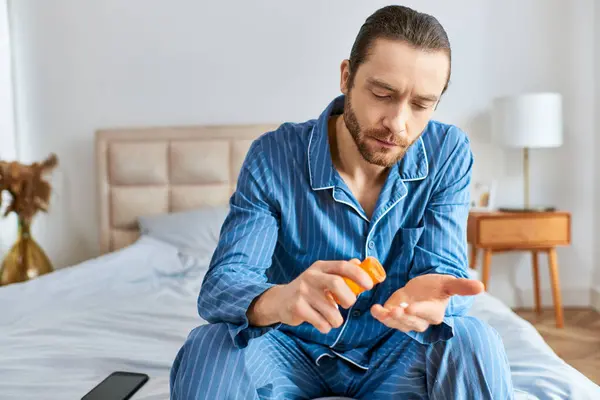 A man doing yoga sits on a bed, taking pills. — Stock Photo