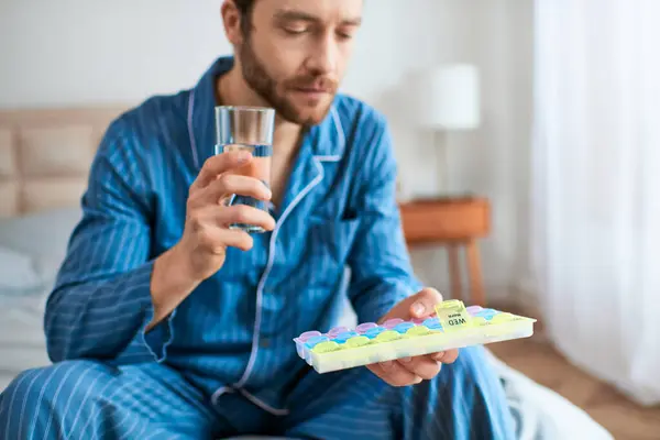 A man relaxing on a bed, holding pills, enjoying his morning. — Stock Photo