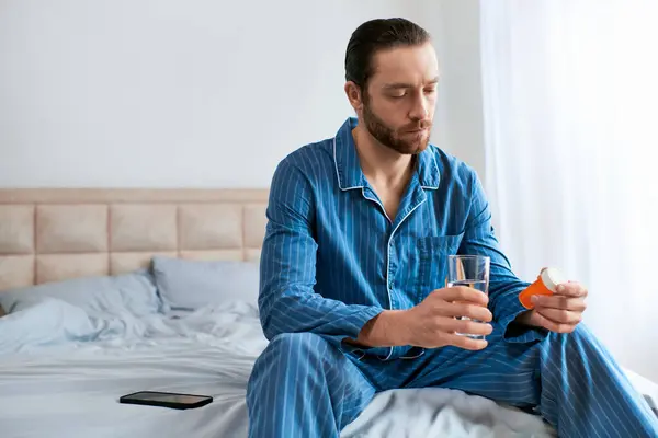 A man sitting on a bed, holding a glass of water. — Stock Photo