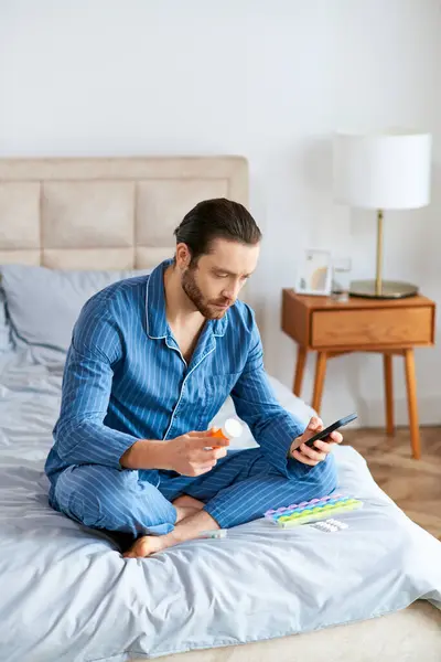 Un hombre pacíficamente se involucra con su teléfono celular mientras está sentado en una cama. - foto de stock