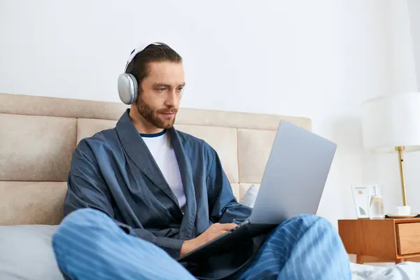 Um homem meditando em uma cama, navegando na web em um laptop. — Fotografia de Stock