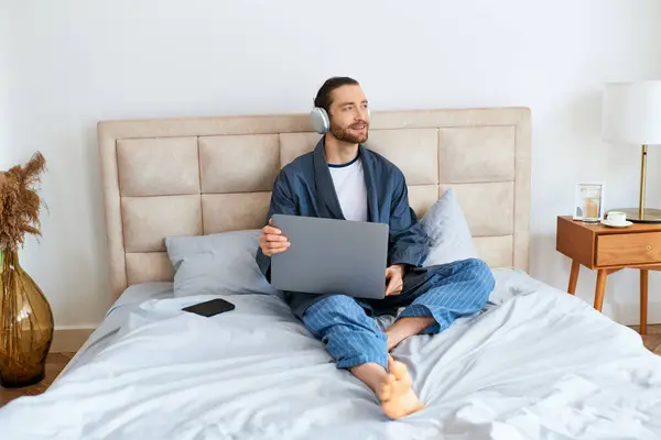 A man using a laptop on a bed. — Stock Photo