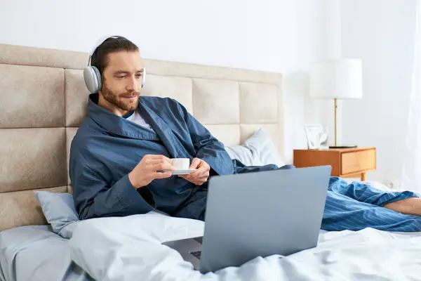 Ein Mann posiert entspannt mit einem Laptop auf dem Bett. — Stockfoto