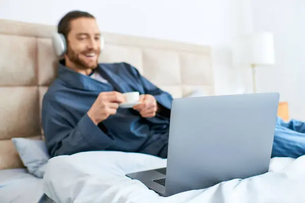 A man in bed engrossed in his laptop screen, creating a serene morning atmosphere. — Stock Photo