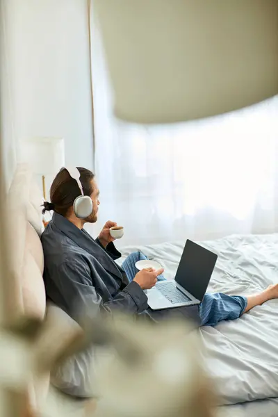Un homme et un homme assis sur un lit avec des ordinateurs portables ouverts, se concentrant sur le travail et la communication. — Photo de stock