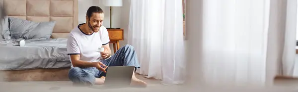 Un homme absorbé dans l'utilisation d'un ordinateur portable tout en étant assis sur le sol. — Photo de stock