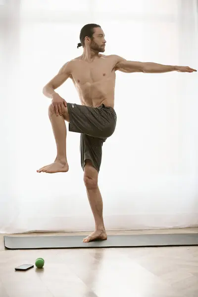 Bello uomo pratica yoga su un tappeto a casa. — Foto stock