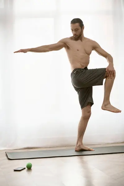 Hombre guapo practicando yoga en una esterilla en su casa durante la mañana. - foto de stock