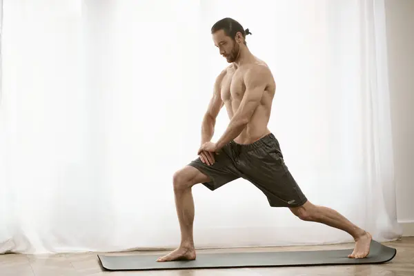 Prática de ioga em casa; um homem, bonito e focado, equilibra graciosamente em um tapete. — Fotografia de Stock