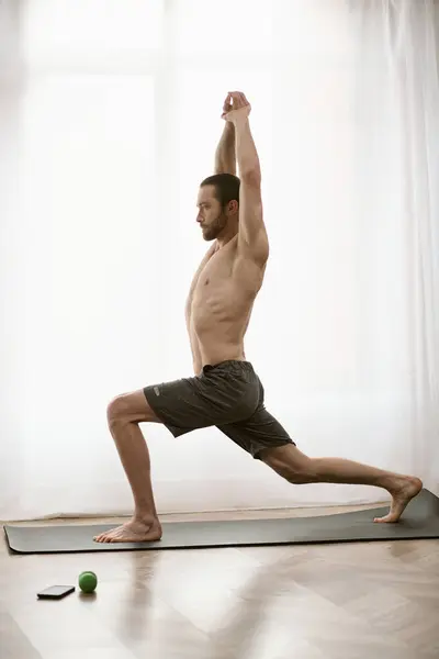 Hombre guapo practicando yoga en una alfombra en casa por la mañana. - foto de stock