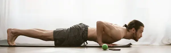Un hombre guapo hace ejercicios en una esterilla de yoga, haciendo flexiones en casa por la mañana.. - foto de stock