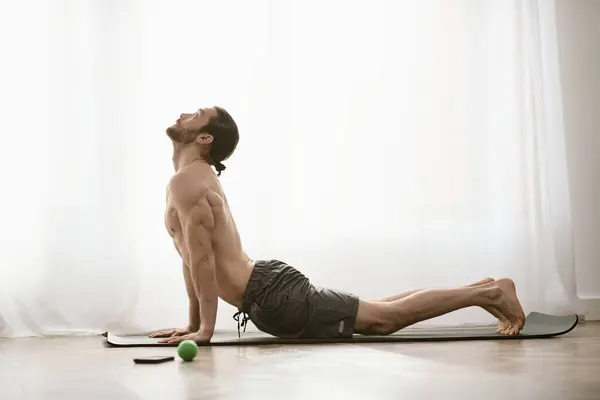 Séance de yoga matinale à la maison avec un homme concentré pratiquant sur un tapis. — Photo de stock