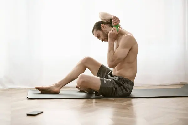 A handsome man peacefully sits shirtless on a yoga mat. — Stock Photo