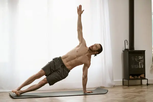 Um homem bonito em sua rotina matinal, praticando ioga em um tapete. — Fotografia de Stock