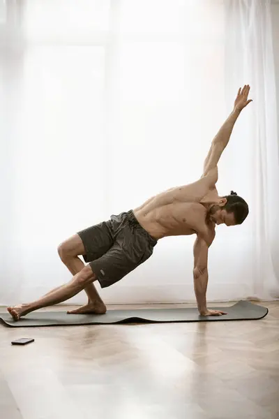 Um homem bonito encontra tranquilidade em seu tapete de ioga como ele pratica uma postura. — Fotografia de Stock