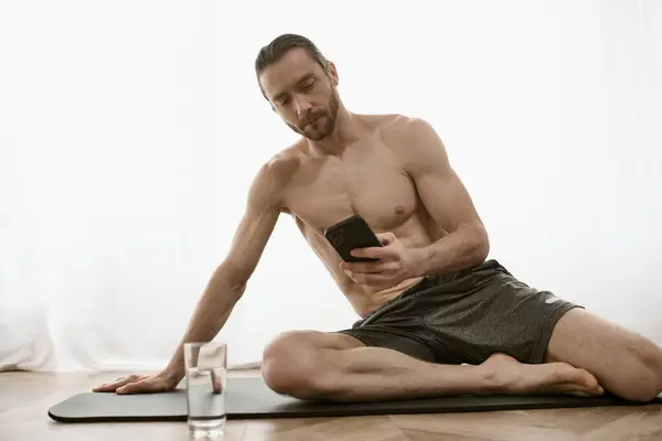 Em casa praticante de ioga no tapete usa telefone celular para sessão matinal. — Fotografia de Stock