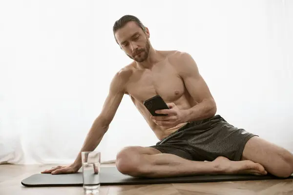 Practicante de yoga en casa en estera utiliza el teléfono celular para la sesión de la mañana. - foto de stock