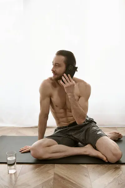 Handsome man on yoga mat chatting on cellphone during morning routine. — Stock Photo